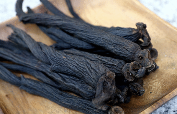 Black ginseng roots with vitamin C capsules on a wooden table