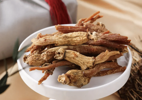 A wooden tray with sliced Korean red ginseng roots and a cup of ginseng tea